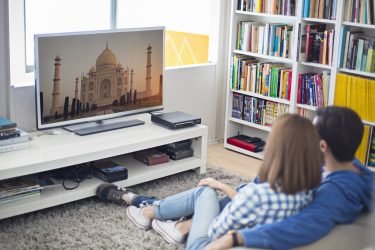 Young couple watching a travel documentary of India, both are very relax and seating on the carpet.